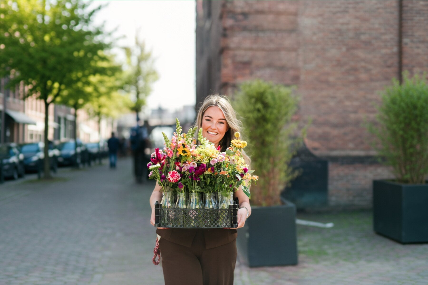 Vrouw met een krat kunstbloemen op een stadsstraat