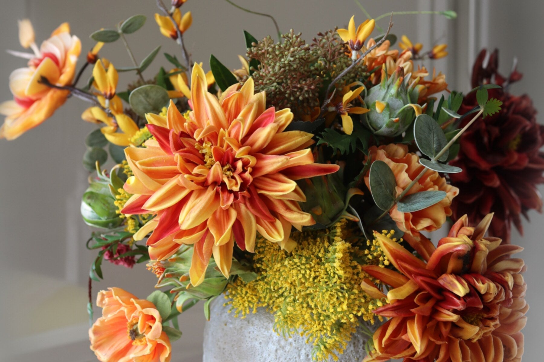 Herfstboeket met oranje kunstbloemen in een vaas