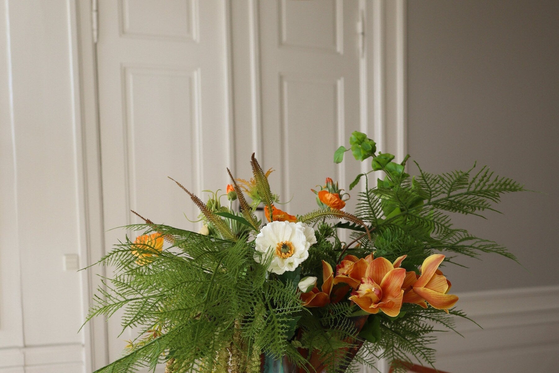 Kunstbloemen arrangement met groen in een lichte ruimte